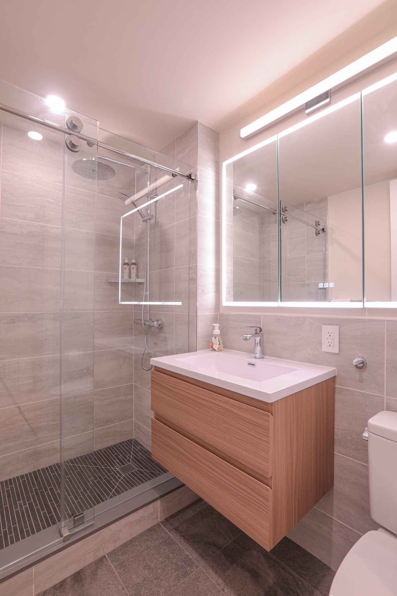 Bathroom — frameless glass shower, floating wood vanity, LED mirror